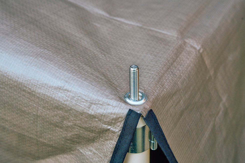 縦方向パイプ先端のピンにひさしのグロメットを通して、その上から張り綱をくくりつけてペグダウンしていく