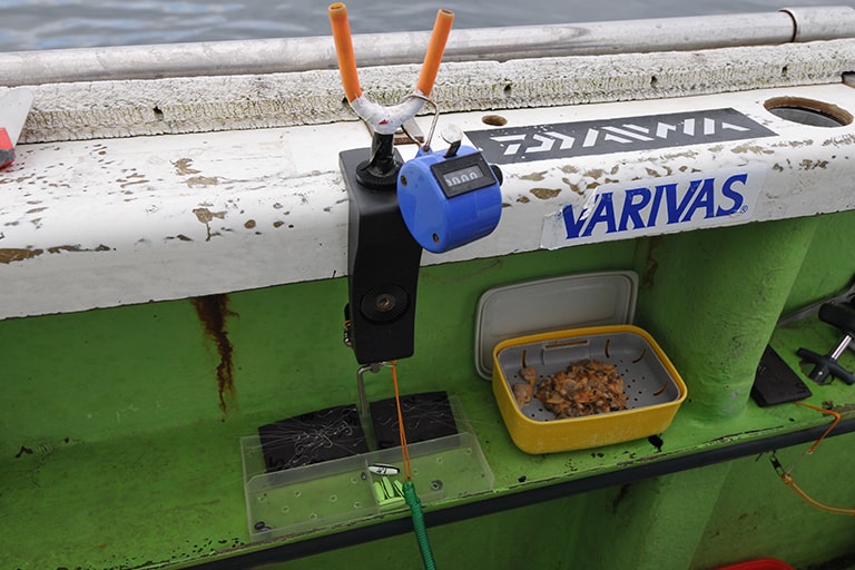 ベテランの釣り座。サオ受けにカウンターがあり、これで数をカウントします。エサのアサリは小出しにして船べりに置き、それ以外はクーラーボックスに