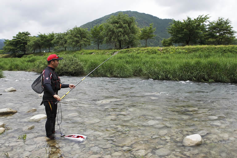 伸ばしたサオ先の真下あたりまでオトリが出たら、もう一方の手（写真では左手）をサオに添えて構える
