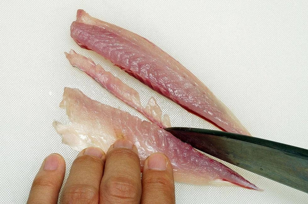 血合骨を処理する方法は2通り。良型アジの場合は背身と腹身に切り分けてから、写真のように間の血合骨を薄くすき取る。