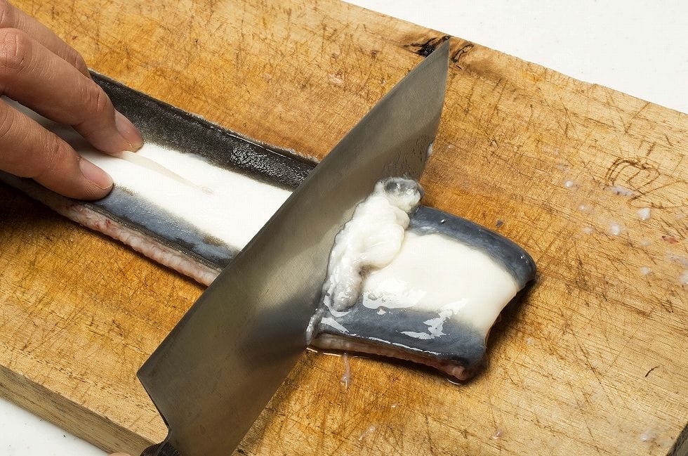 皮目を上にしてまな板に並べ直し、包丁の峰を動かすと白濁したヌメリをきれいすっきりとこそげ落とすことができる。