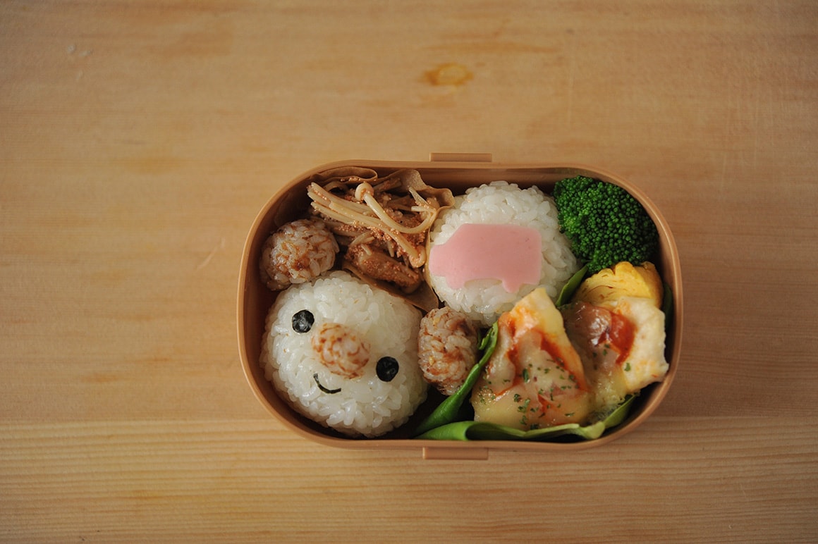 6. 海苔をハサミでカットして、目・口を作り5の顔のおにぎりに貼る。もう一方のおにぎりに4のハムを置く。